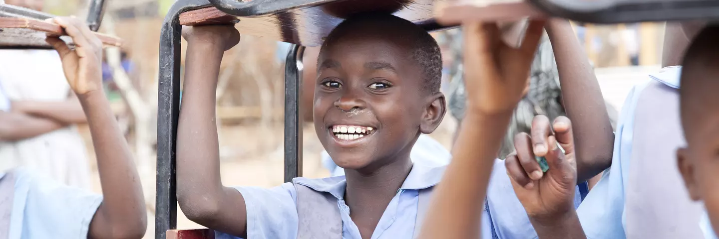 Student at St. Ignatius secondary school carrying a chair over her head