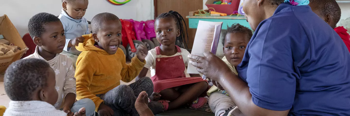 A teacher reads a book to children at Mzingisi daycare