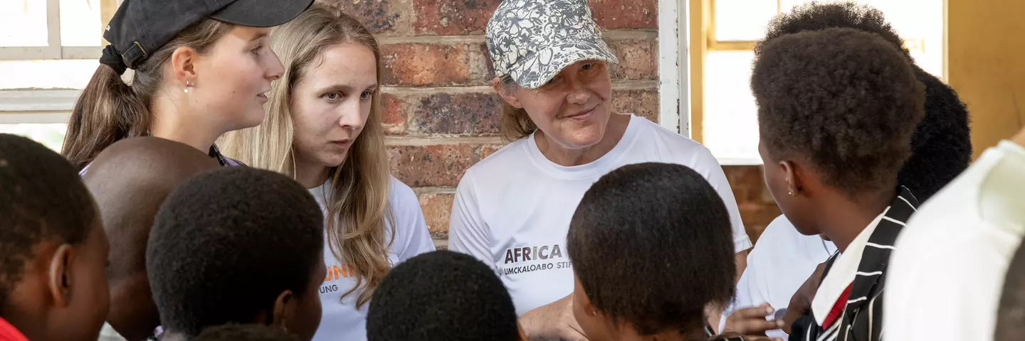 Project-visit participants at Ekuphumleni Secondary School in South Africa talking with students.