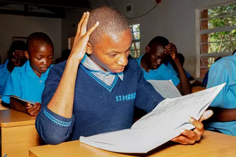 Ein Schüler der St. Mauritius-Sekundarschule schaut im Unterricht in ein Schulbuch.