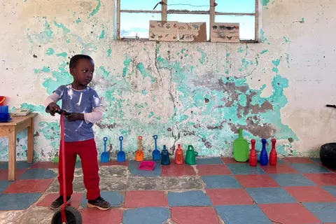 Ein Junge mit Roller in der Kita Sizamile Educare