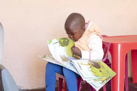 Ein Kind in einer Kita der Samara-Stiftung schaut ein Kinderbuch an