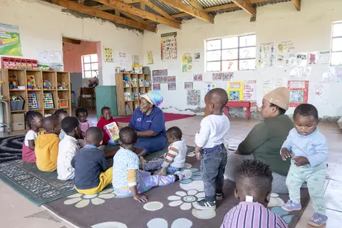 A teacher reads a book to children at Mzingisi daycare.