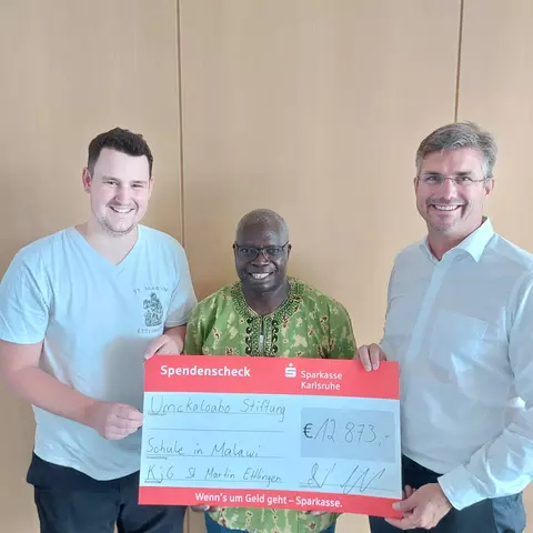 Father John Moyo receives a donation from the catholic youth organization KJG