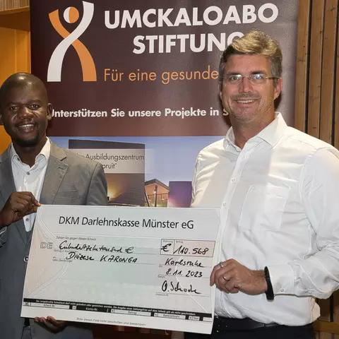 Mwawi Shaba aus Malawi nimmt von Olaf Schwabe den Scheck über 110.000 Euro für den Bau der St.-Steven's-Schule entgegen.