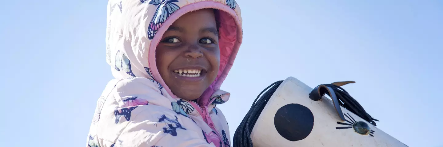 Ein Kind in einer Kita in Südafrika sitzt auf einem Spielgerät.