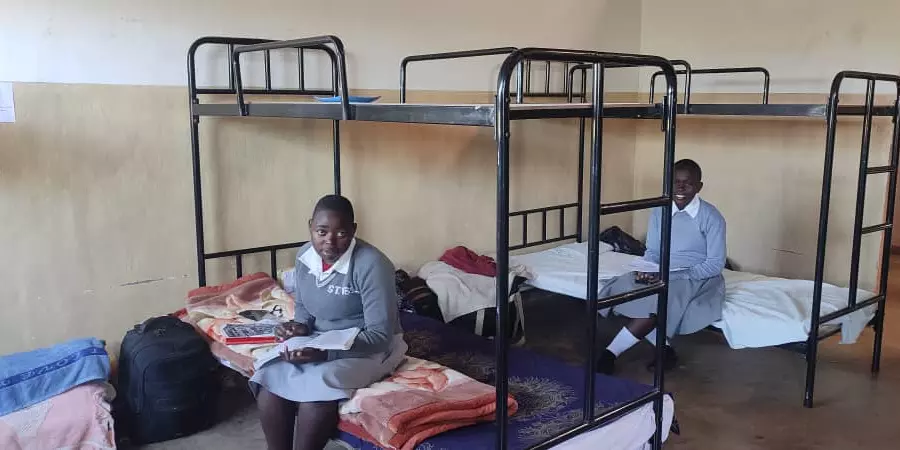 Two schoolgirls sit in a new dormitory at St. Ignatius boarding school in Nthalire