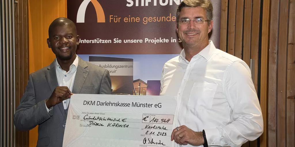 Mwawi Shaba aus Malawi nimmt von Olaf Schwabe den Scheck über 110.000 Euro für den Bau der St.-Steven's-Schule entgegen.