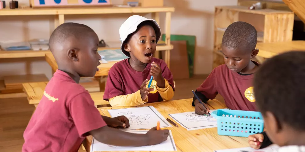 Kinder im Montessori-Kindergarten im Walmer Township, Südafrika, malen an einem Tisch