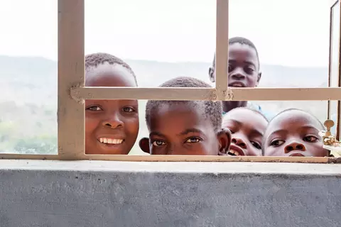 Fröhliche Kinder schauen durch ein Fenster