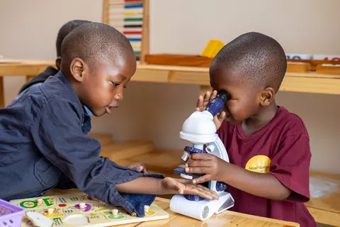 Zwei Kinder im Montessori-Kindergarten im Walmer Township, Südafrika, experimentieren mit einem Mikroskop