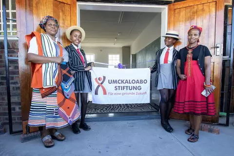Lehrerinnen und Schülerinnen der Ekuphumleni-Sekundarschule mit einem Banner der Umckaloabo-Stiftung, die die Schule seit vielen Jahren finanziell unterstützt.