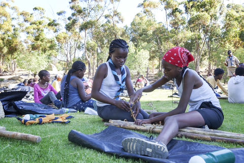 Girl Scouts knot together timbers for a hut
