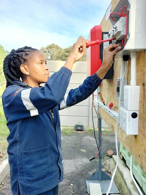 Eine junge Frau arbeitet an einem elektrischen Schaltbrett.