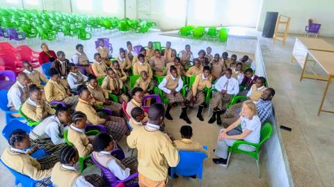 Eine Besucher aus Deutschland beantwortet die Fragen der versammelten Schülerinnen und Schüler der Ekuphumleni-Sekundarschule in Lusaka, Sambia.