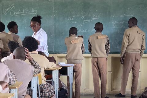 Eine Chemie-Lehrerin der Ekuphumleni-Sekundarschule in Sambia erklärt die Bindungsfähigkeit von Elektronen auf sehr praktische, augenzwinkernde Weise.
